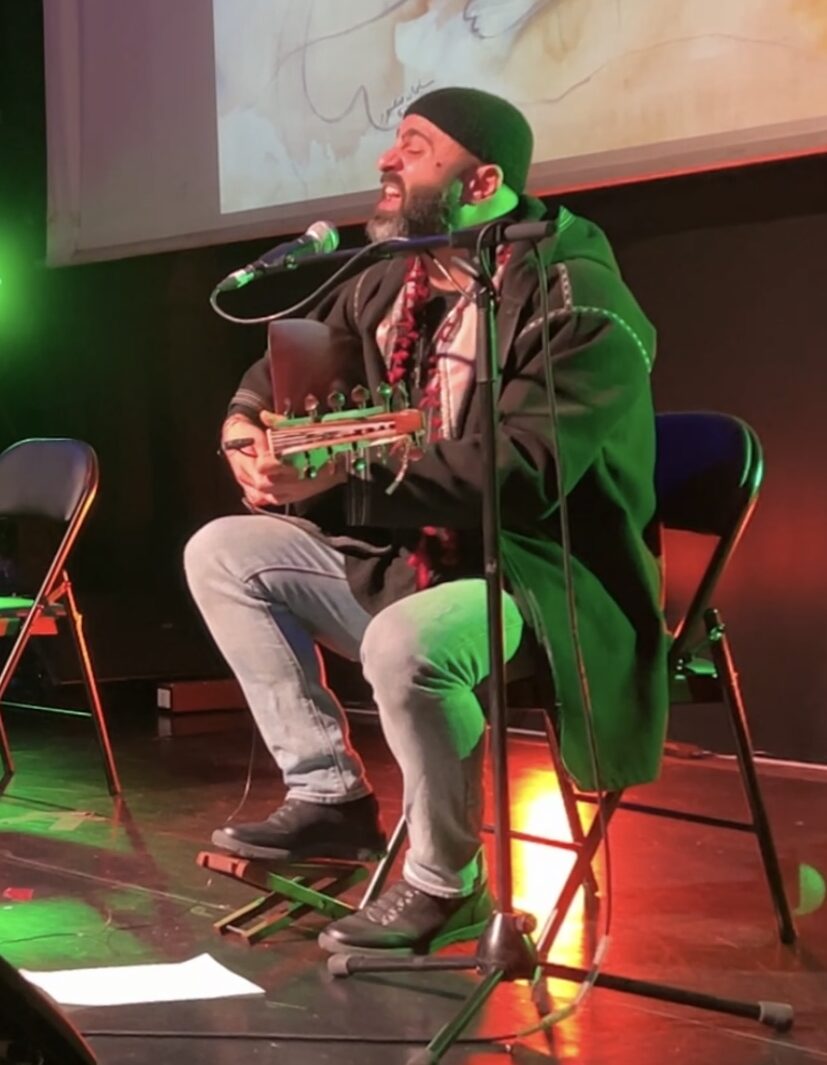 A performer sings and plays guitar on stage.