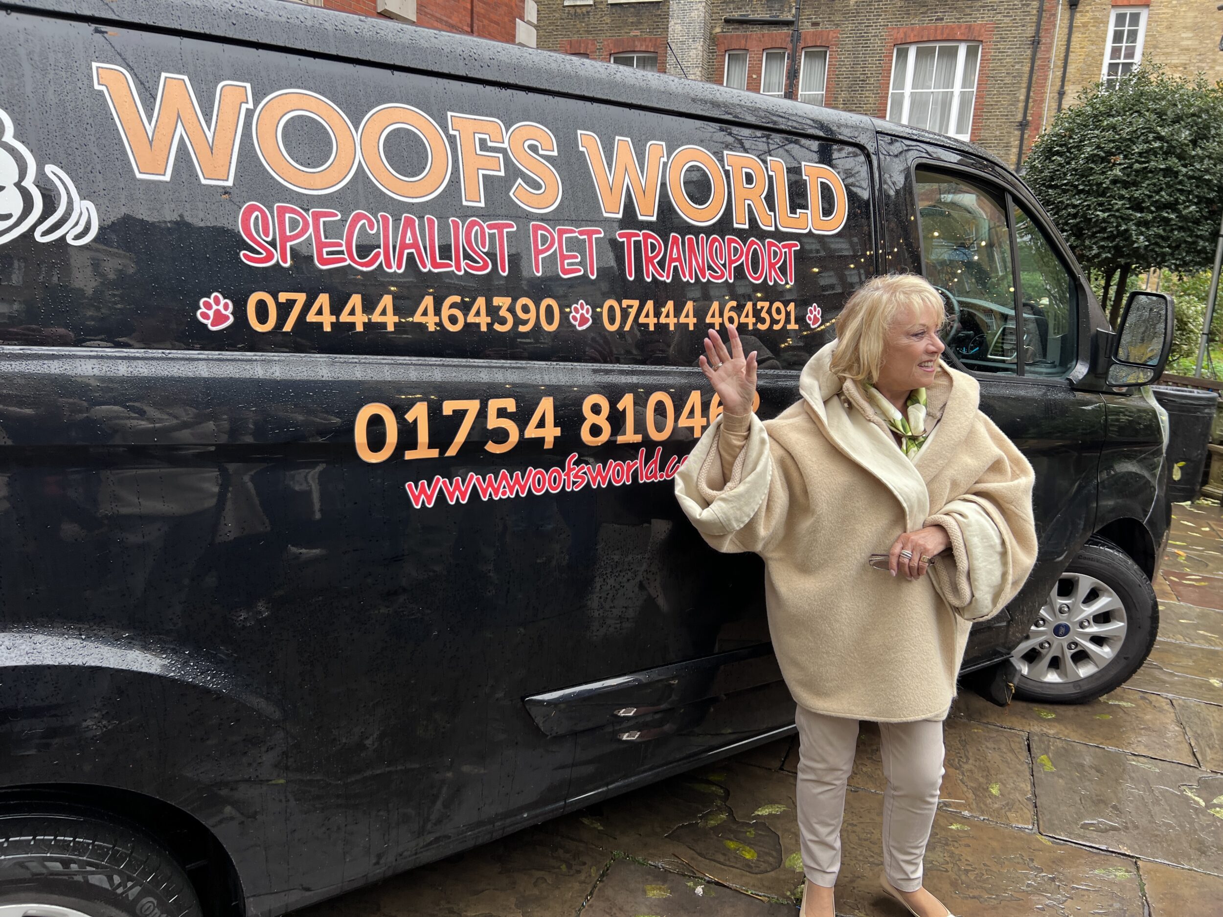 Elaine Paige O.B.E. standing in front of a pet transport van.