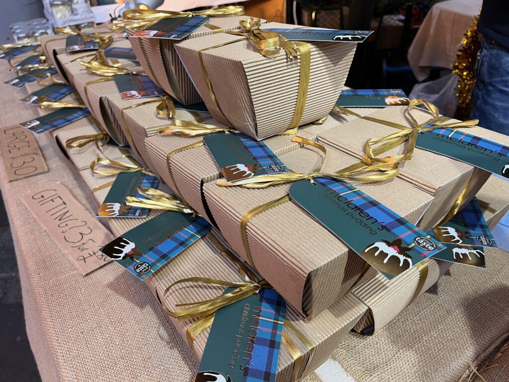 Christmas puddings in boxes with labels stacked on stall at market