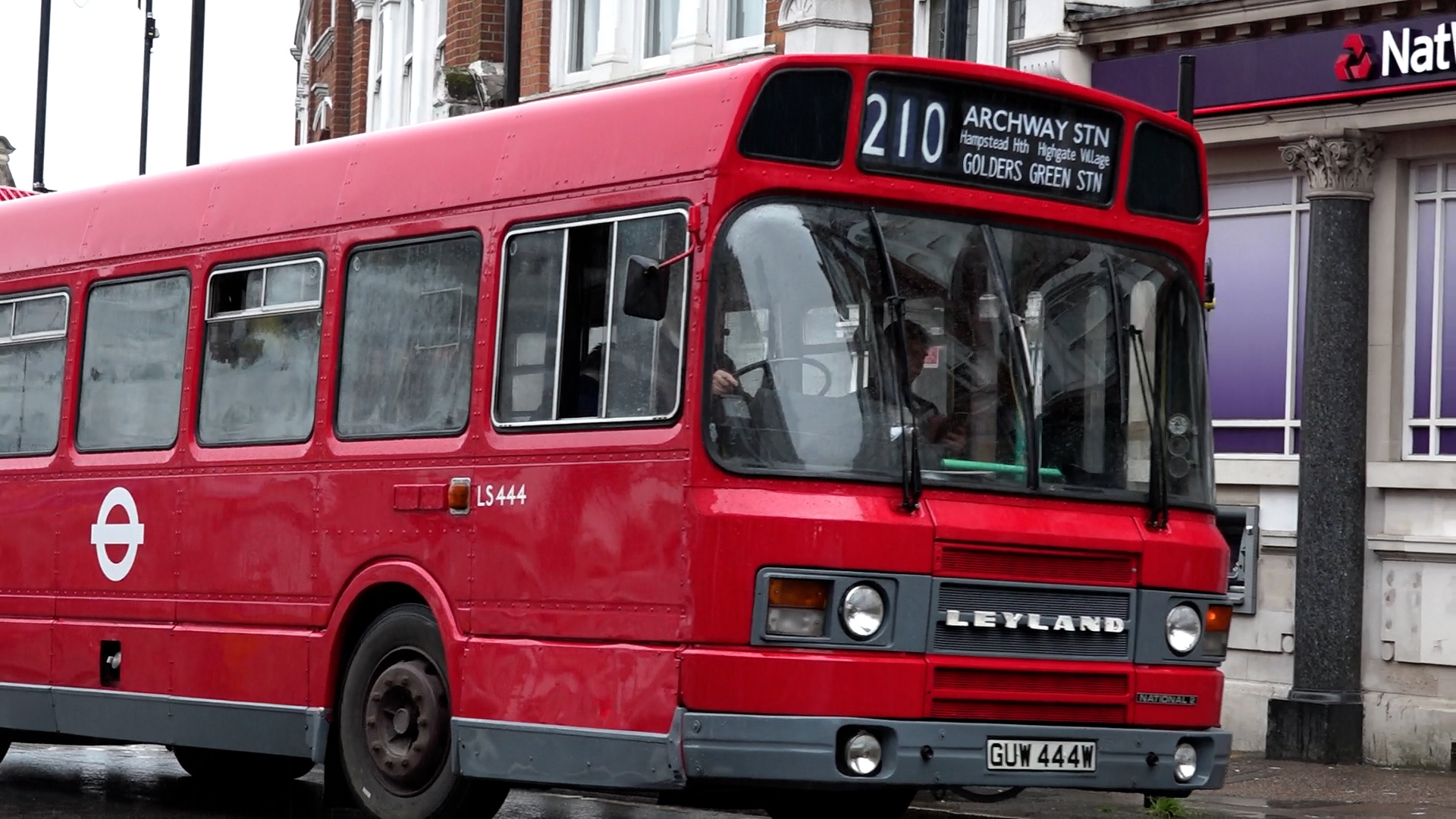 Wide shot of vintage red bus on the 210 route in North London