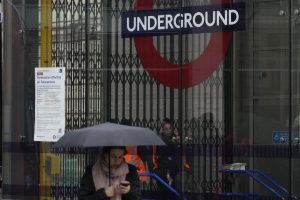 A London Underground worker seen through the closed barriers of a tube station, during a strike by members of the Rail, Maritime and Transport union (RMT), in central London, Tuesday, March 1, 2022. Travellers in London are being warned of severe disruption to Tube services because of strikes by thousands of workers in a dispute over jobs, pensions and conditions. (AP Photo/Alastair Grant)