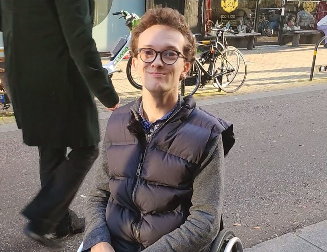 Happy young disabled man in a wheelchair, in Exmouth Market.