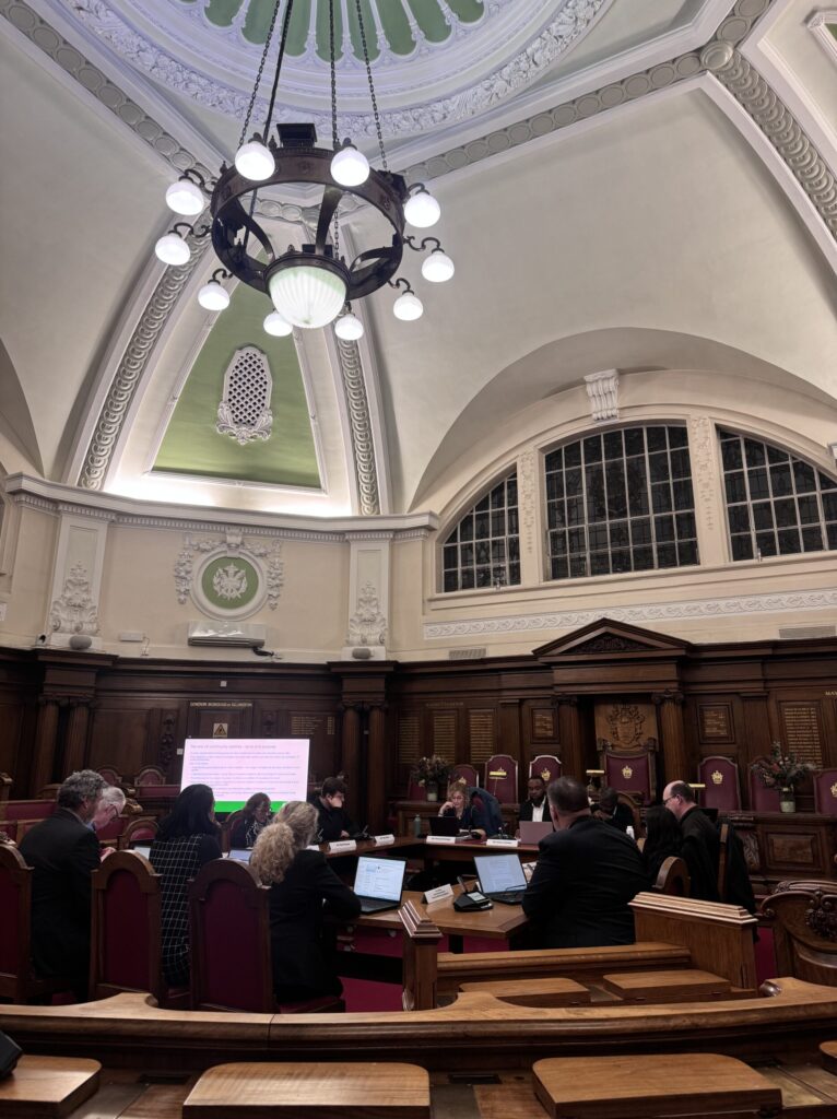 Islington Councillors at Islington Town Hall's Council Chamber gather around a large table for a committee meeting 