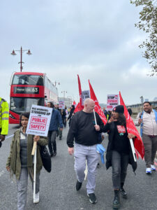 Protestors crossing Blackfriars Bridge walking towards the TfL headquarters in Southwark, carrying signs reading ‘Bus Workers: Standing up for Public Safety’ and ‘Stop the Fatigue Danger!”