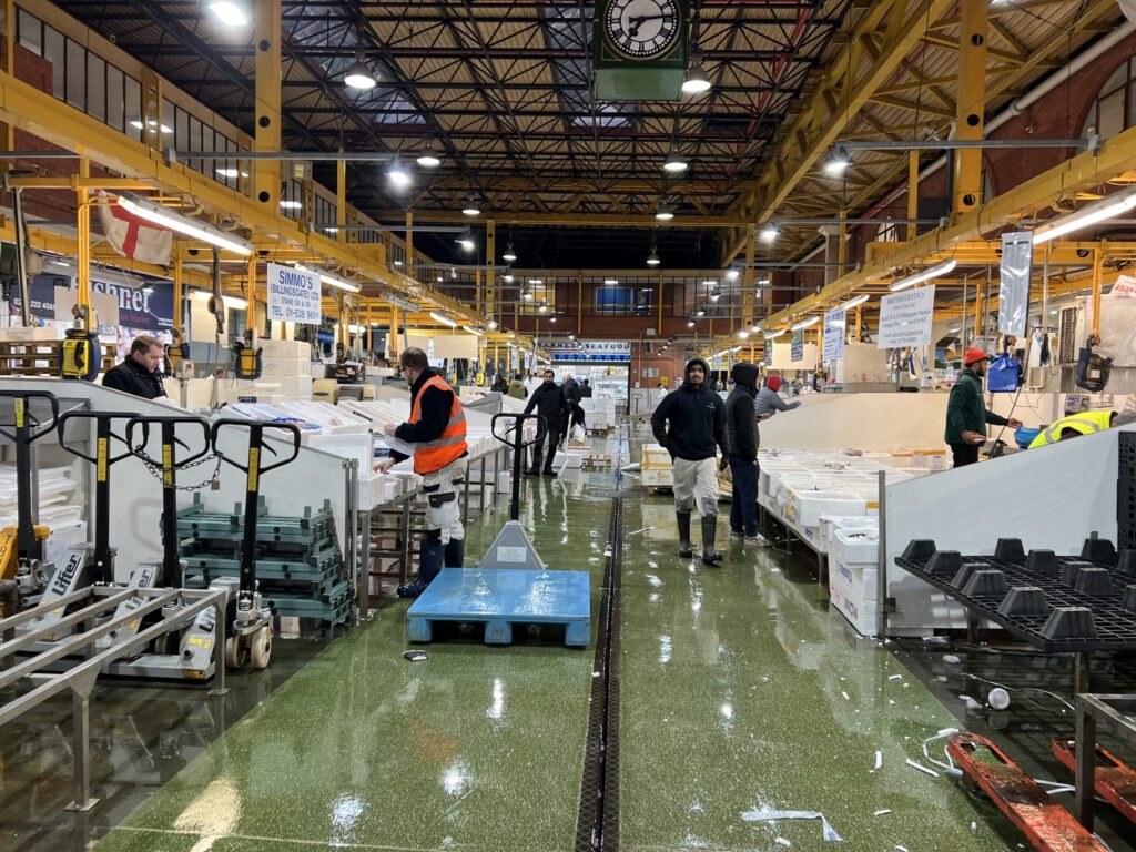 Inside of Billingsgate market. Traders pack up boxes of fish.