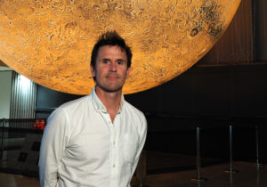 Artist Luke Jerram stands in front of his yellow, illuminated Mars installation.