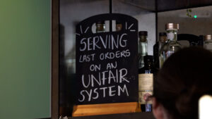 Pub sign saying 'serving last orders on an unfair system'.