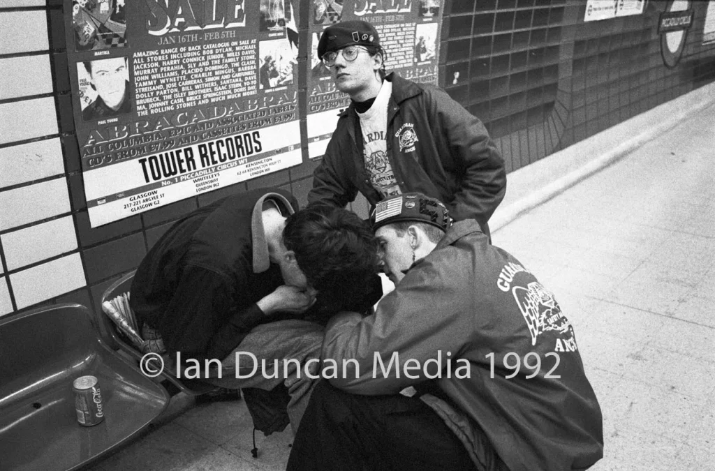 Black and White image of Guardian Angel volunteers helping a drunk man on a tube platform in 1992