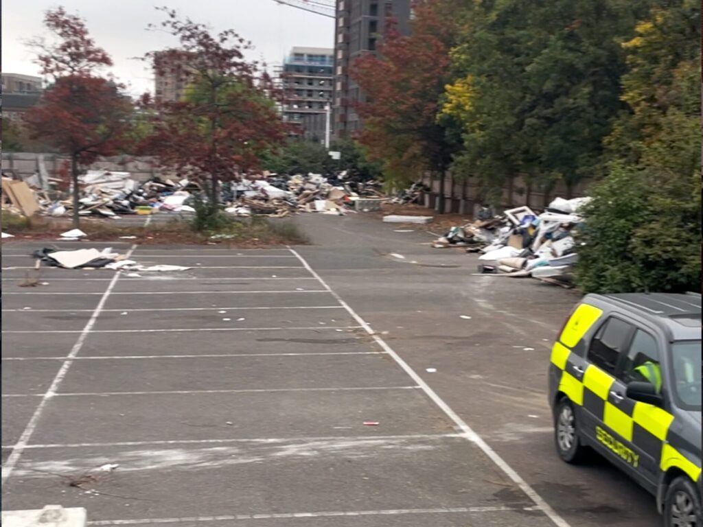 Image of the fly tip in Barking, with a security car. 