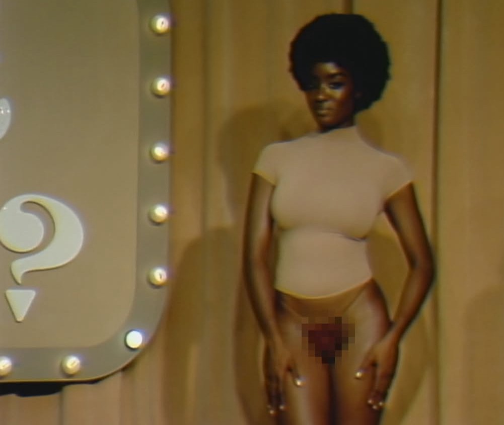 Women in t shirt wearing thong with red curly wig on top of it