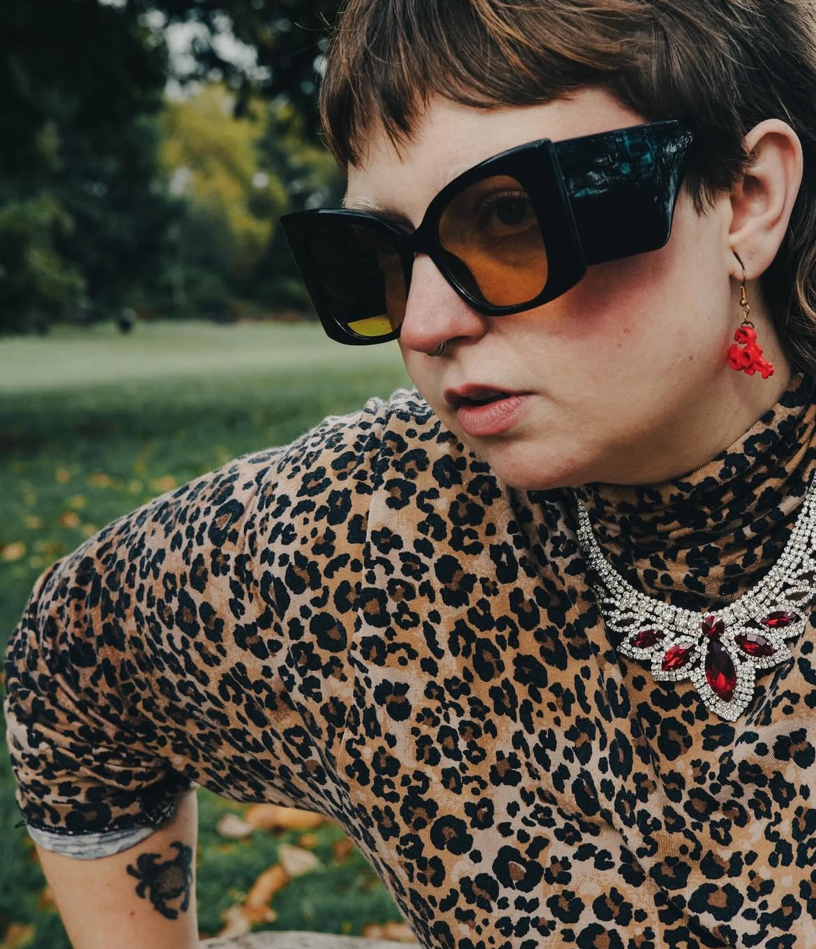 Meg wearing a leopard print top looking to the left with sunglasses on