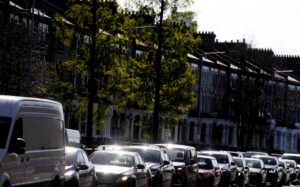 Traffic on a residential street in London with cars and vans lined up during daylight