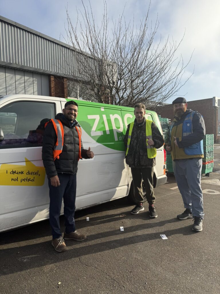 Three volunteers stand in front of a Zipcar van