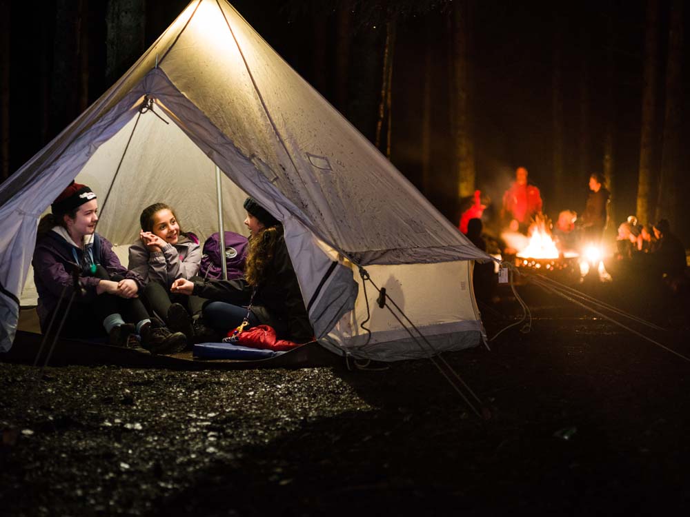 cub members in a tent with a campfire in the background