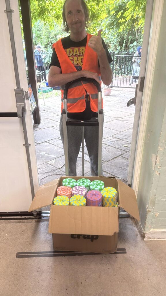 A volunteer with a trolley carrying boxes of toilet paper