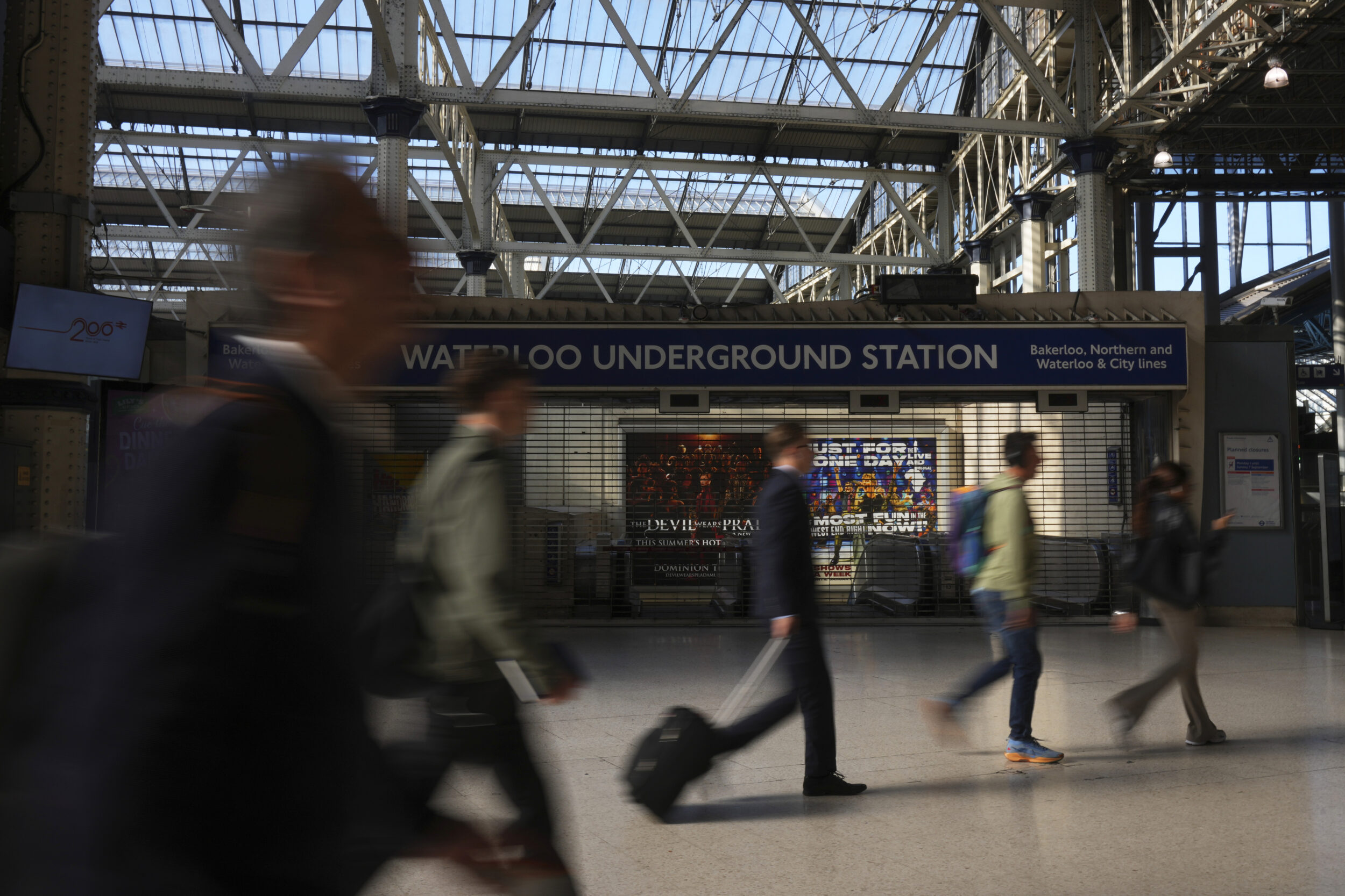 Commuters walk past a closed Waterloo Station.